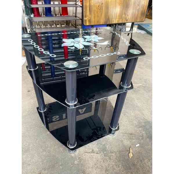 Meuble TV de haute qualité avec 3 tablettes ovales en verre noir brillant et des pieds noirs.